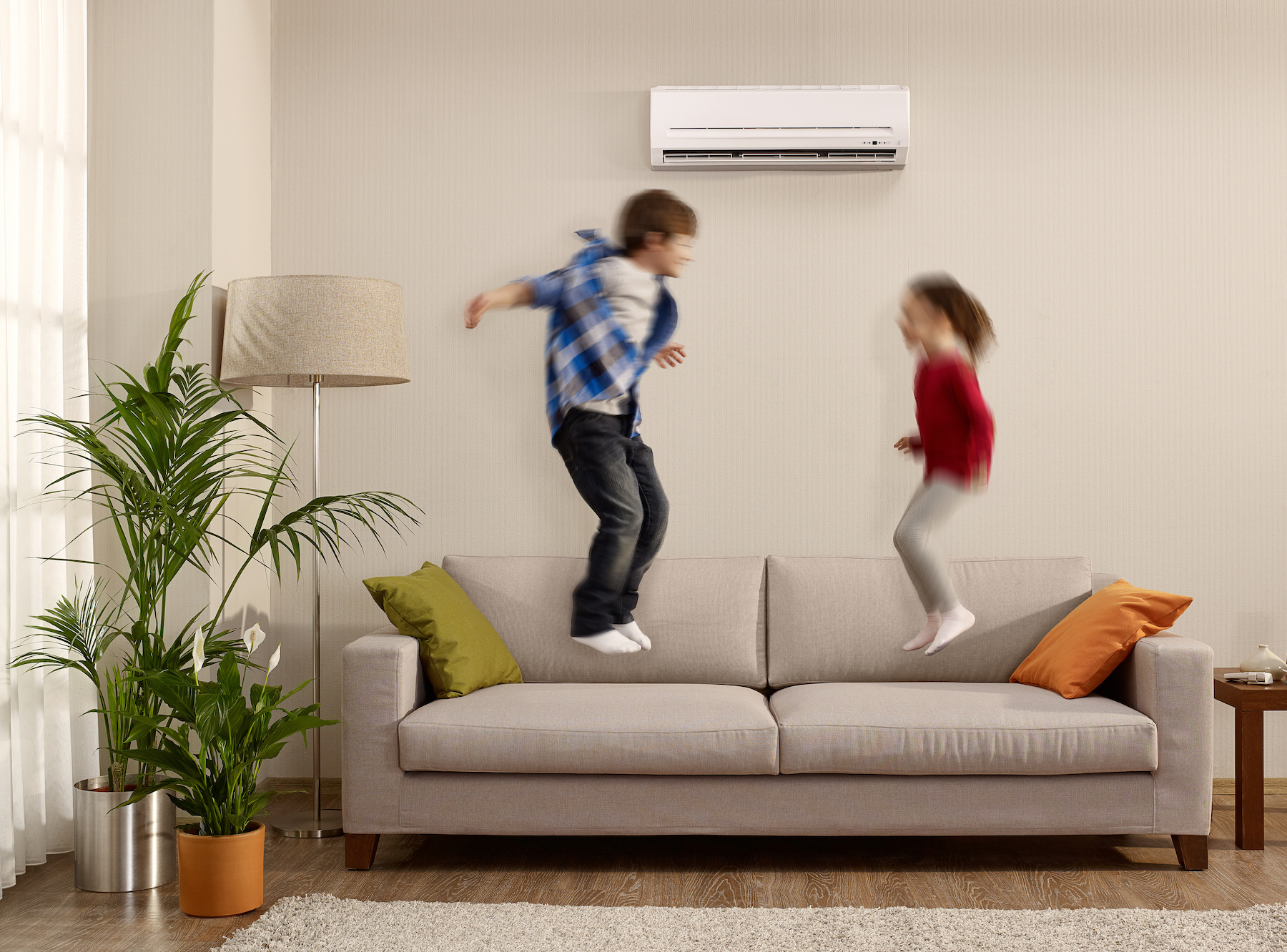 Raumklimaanlage - darunter springen Kinder auf dem Sofa